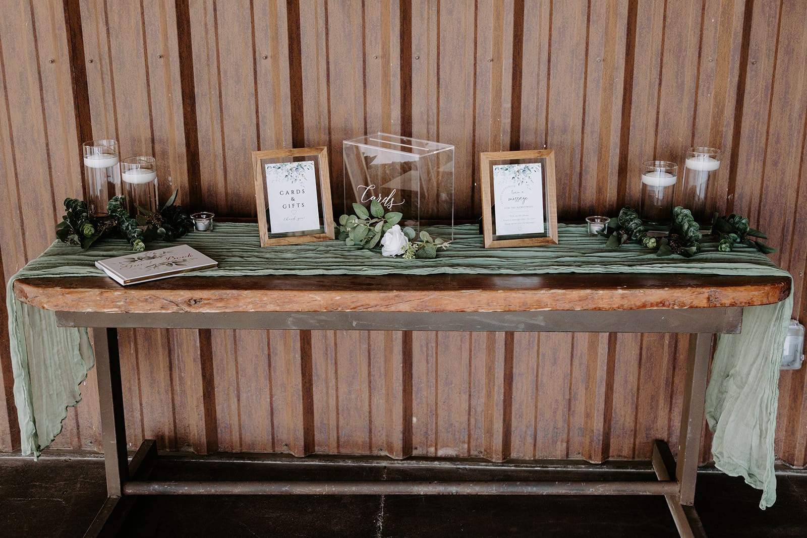 Welcome wedding table with green and wood accents